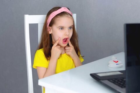 Cute little girl sitting in front of the laptop