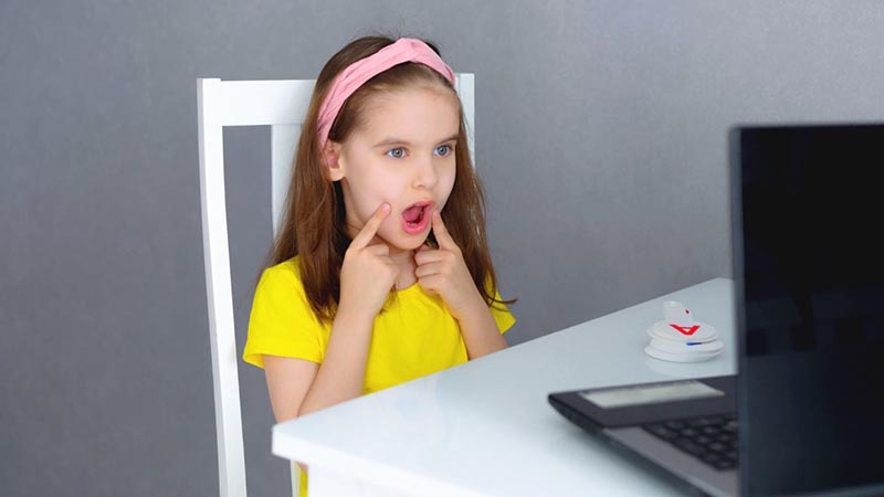 Cute little girl sitting in front of the laptop