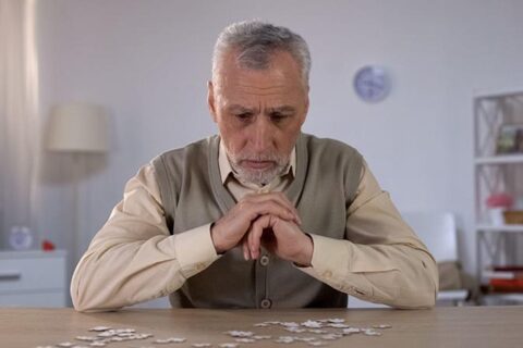 Tense old man sitting on the chair at the home