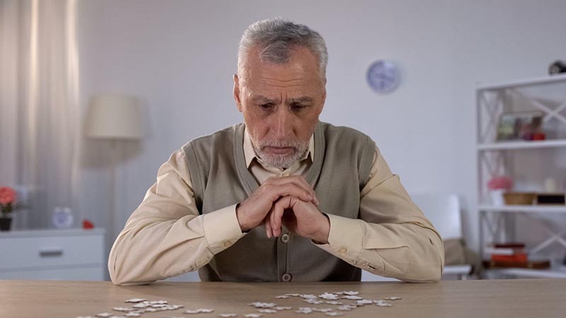 Tense old man sitting on the chair at the home