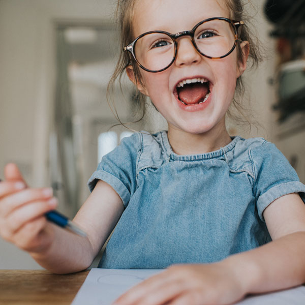 little girl with glasses writing on paper