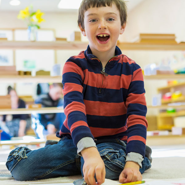 young boy smiling while doing school activity