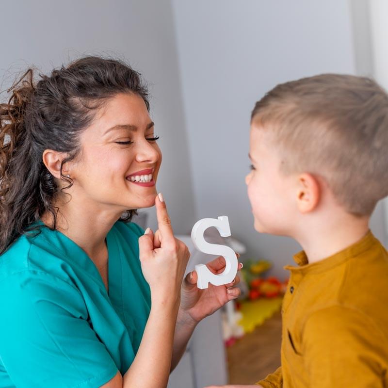 speech pathologist teaching a boy to say "s"
